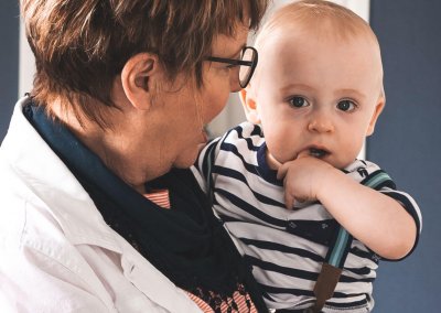 A small child held by a woman looks at the camera