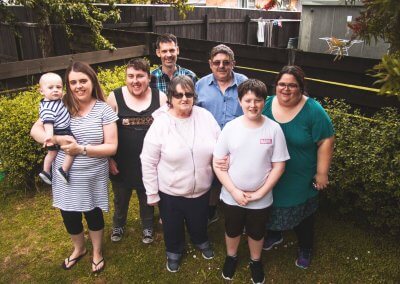 A family standing in a garden, smiling at the camera