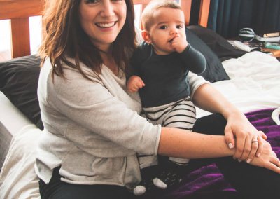 A mother and her baby son sitting on a bed in a brightly lit room