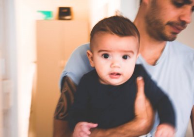 A small baby in his father's arms looking at the camera