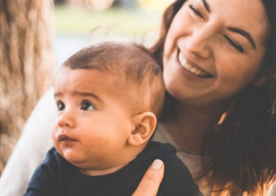 A mother smiles while holding her baby son
