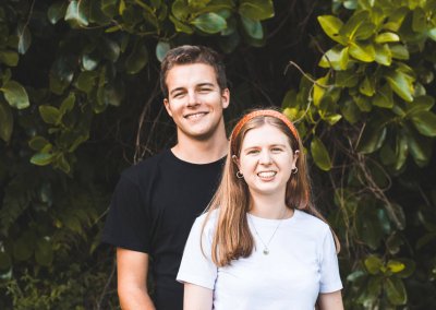A young couple standing together in front of a backdrop of trees