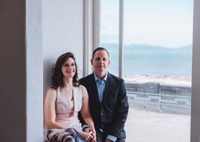 A couple sitting by a window looking out to sea